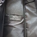 Detail vnitřku černé brašny nebo pouzdra z textiledního materiálu. Na vnitřní kapsi je přišitá černá štítková nášivka s bílým logem MUSICAREA a nápis…