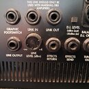 Detail zadní strany černého hudebního zesilovače s řadou konektorů a popisky. Jsou zde vidět vstupy a výstupy s nápisy GRAPHIC FOOTSWITCH, LINK IN, L…