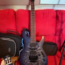 Modrá elektrická kytara s grafickým motivem stromu na těle a špičatou hlavou. Na hlavě je viditelné logo Ibanez. Kytara má dva humbuckery, tremolo mo…