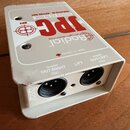 Bílý kovový box s nápisy Radial engineering, JPC STEREO PC DI BOX a MK3. Na zadní straně jsou dva XLR konektory s popisky Isolated OUT-RIGHT 600Ω a I…