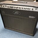 Kytarový kombo zesilovač s černým potahem a stříbrným ovládacím panelem. Na panelu je nápis 6505+ 112 a logo Peavey. Přední mřížka je černá s vyšívan…