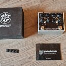 Na fotografii je stříbrný kytarový pedál s nápisem MICROTUBES P7K ULTRA a logem Darkglass Electronics. Vedle pedálu je černá krabice a černá karta, n…