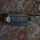 Elektrický kytarový snímač s kovovým krytem a černým plastovým základem. Na krytu je nápis „Seymour Duncan“ s doprovodnými logy a text „Made in Ameri…