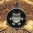 Fotografie zachycuje zadní stranu elektronického bubnového padu značky Roland. Uprostřed je bílý kruh s černým nápisem Roland a nad ním označení mode…