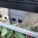 Detail zadní strany černého zesilovače s konektory. Jsou zde viditelné vstupy a výstupy s popisky FOOTSWITCH, FX LOOP (SEND, RETURN) a varovný nápis…