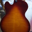 Zadní strana kytary s výraznou plamenovou strukturou dřeva. Povrch má červenohnatý gradient (sunburst) přecházející do žluté barvy ve středu. V horní…
