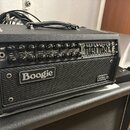 Černý kytarový zesilovač s nápisem JP-20 na ovládacím panelu a velkým logem Boogie na přední mřížce. V pravém dolním rohu je malý štítek s nápisem Me…