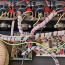 Fotografie zachycuje vnitřek elektronického zařízení s černým chladičem, na kterém jsou umístěny čtyři černé ventilátory. Na chladiči jsou přišroubov…