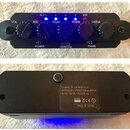 Černý efektový pedál s pěti otočnými knoflíky popsanými jako VOL, MIC, DELAY, REVERB a CHORUS. Na horní straně jsou čtyři modré kontrolky a nápisy PO…