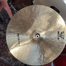 Kruhové mosazný činely s viditelným broušením povrchu. Na ploše je vyražen nápis AGEAN a text HI-HAT TOP MEDIUM 14" 35 cm. V horní části jsou viditel…