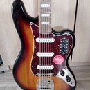 Elektrická kytara s tělem v provedení sunburst a červeným želvovinovým pickguardem. Na těle jsou tři bílé snímače a stříbrný most. Na pickguardu je n…