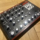 Synthesizer Roland PG 200 v černé barvě s červeným pruhem. Na horní straně je bílý nápis Synthesizer a logo Roland PG 200. Přístroj obsahuje numerous…