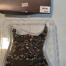 Sada předmontovaného pickguardu s mechanismy snímačů v průhledném plastovém obalu. Pickguard má černý mramorovaný vzor a tři černé snímače s bílým lo…