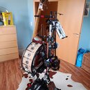 Na fotografii je zobrazen hybridní nástroj kombinující tělo bubnu a krk kontrabasu v dřevěném provedení. Na těle bubnu jsou viditelné ozdobné kovové…
