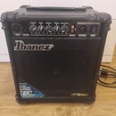 Černý kytarový kombo zesilovač značky Ibanez. Na horním ovládacím panelu jsou nápisy Sound Wave cu, VOLUME, BASS, MIDDLE, TREBLE a PRESENCE. V dolní…