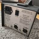 Zadní strana stříbrného elektronického zařízení s černou rukojetí, na které je nápis AUDIO. Na šasi jsou texty UNIVERSAL AUDIO, INC. SANTA CRUZ, CALI…