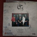 Zadní strana vinylové desky s motivem mramorového pozadí. Uprostřed je fotografie pěti osob v maskách a kostýmech, nad nimi je černé stylizované logo…