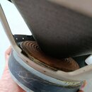 Detailní pohled na zadní část reproduktoru. Je vidět hnědý papírový kužel a spodní kovový rám s černým gumovým nebo plastovým prstencem. Povrch spodn…