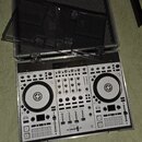 Stříbrný DJ kontrolér v hliníkovém přepravním kufru s černé pěnovou výplní. Na zařízení je v levém horním rohu nápis TRAKTOR KONTROL S4. Kontrolér ob…