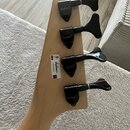 Detail hlavy kytary z přírodního světlého dřeva se čtyřmi černými ladicími mechanismy. Na každém z nich je bílý nápis Jackson. Vedle jednoho z mechan…