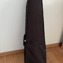Černý textilní pouzdro (gig bag) na hudební nástroj. Pouzdro má obdélníkový tvar se zaobleným horním okrajem a v dolní části je vidět zipovaná kapsa.…