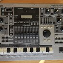 Stříbrný sekvenční sampler Roland MC-505 groovebox. Na předním panelu jsou viditelné nápisy Roland MC-505 a groovebox, řada ovládacích knoflíků, posu…