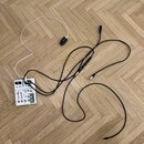 Bílý efektový pedál s černými ovládacími prvky a nápisy, včetně loga BOSS v pravém dolním rohu. K pedálu je připojen bílý napájecí adaptér a dva čern…