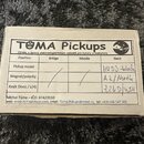 Fotografie zachicuje bílou papírovou krabičku s tabulkou specifikací. V horní části je nápis TOMA Pickups a text Výroba a opravy elektromagnetických…