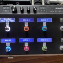 Černý kytarový efektový pedalboard s nápisem LINE 6 HX EFFECTS. Horní část obsahuje ovládací knoflíky a tlačítka SAVE, ACTION a HOME. Spodní část obs…