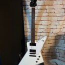 Bílá elektrická kytara s černým hmatníkem a černými snímači. Na hlavě je viditelné logo Gibson. Tělo má hranatý, asymetrický tvar a povrch vypadá čis…