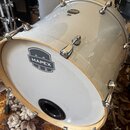 Stříbrný basový buben s bílým předním koženem. Na koženě je černé logo MAPEX. V horní části korpusu je malý oválný nápis MODEL. Nástroj má chromované…