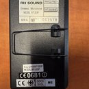 Fotografie zachycuje zadní stranu černého elektronického zařízení s kovovým držákem. Na bílých nálepkách jsou uvedeny nápisy RH SOUND, Wireless Micro…
