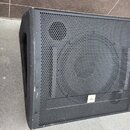Dva černé reproduktory s kovovou mřížkou. Na pravém reproduktoru je v dolní části bílý čtvercový štítek s nápisem the box. Povrch je viditelně opotře…