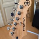 Fotografie zachicuje hlavu elektrické kytary z přírodního světlého dřeva s chromovanými ladičkami. Na hlavě je umístěno kulaté logo Yamaha a nápis PA…