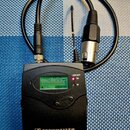 Černý bezdrátový přijímač s nápisem SENNHEISER a označením EW 100 G2. Zařízení má malý LCD displej s indikátory MHz, RF, AF a Pilot, oraz tlačítko MU…