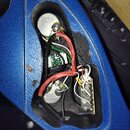 Fotografie zachycuje vnitřek modrého přístroje s otevřeným servisním otvor. Uvnitř jsou vidět elektronické součástky, kabeláž a dvě kovové válečkovit…