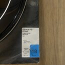 Fotografie detailu obalu na bubnovou blanu. Na bílé nálepse je uveden text ES-0618-PS-812448, PINSTRIPE® EBONY®, Batter a informace o importéru GEWA…