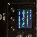 Detailní záběr na displej a ovládací prvky černého elektronického zařízení. Na modrém displeji je text 02A Torn SC, Mod/Chorus Echo, Time 1/4, Feedbk…