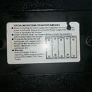 Fotografie detailu bílé nálepky s nápisem SPECIAL INSTRUCTIONS FOR BATTERY AMPLIFIER na černém texturovaném povrchu. Text obsahuje pokyny k připojení…