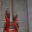 Elektrická kytara s červeným lakovaným tělem a hnědým hnedým krčkem. Na hlavě je viditelné logo Ibanez, na hradle jsou dva humbuckery s nápisem DiMar…