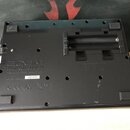 Zadní strana černého elektronického zařízení z plastu. Je zde vyryt nápis ZOOM CORPORATION a text Designed by ZOOM in Japan, Assembled in China. Na b…
