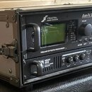 Černý rackový case obsahuje dvě zařízení. Horní jednotka je procesor s nápisy FRACTAL AUDIO SYSTEMS, Axe-Fx II XL a PREAMP/EFFECTS PROCESSOR. Spodní…