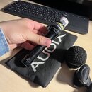 Černý dynamický mikrofon s nápisem AUDIX a označením modelu OM-3b. Na spodní části je nápis MADE IN USA a symbol CE. Mikrofon je v ruce nad černým po…