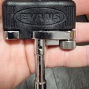 Černý plastový klamp s chromovaným kovovým mechanismem. Na horní části je vyražen nápis EVANS v oválném rámu. Nástroj vykazuje mírné známky používání…