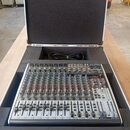 Míchací pult v ochranném přepravním kufru s černým polstrováním. Na horním pravém rohu je viditelné logo "Behringer". Zařízení obsahuje řadu faderů,…