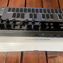 Stříbrno-černý analogový sekvencer s klávesami a ovládacími knoflíky. Na černé části je bílý nápis DONNER SYN BASS ANALOG SYNTHESIZER AND SEQUENCER a…