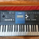 Černý digitální klavír značky YAMAHA s modelem EZ300. Nástroj má bílé a černé klávesy, dvě integrovaná reproduktory po stranách a ovládací panel s di…