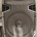 Černý reproduktor s kovovou mřížkou a plastovým rámem. V dolní části je umístěno logo s nápisem RH SOUND. Vedle reproduktoru je vidět část černého mi…