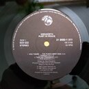 Fotografie detailu středu černé vinylové desky s bílým štítkem. Na štítku je uveden název kapely MEGADETH a album RUST IN PEACE, dále nápisy SIDE 1,…