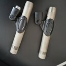 Dvě stříbrné kondenzátorové mikrofony s černými držáky. Na každém držáku je vyražen nápis "PRO-24". Povrch mikrofonů i držáků je v dobrém stavu bez v…